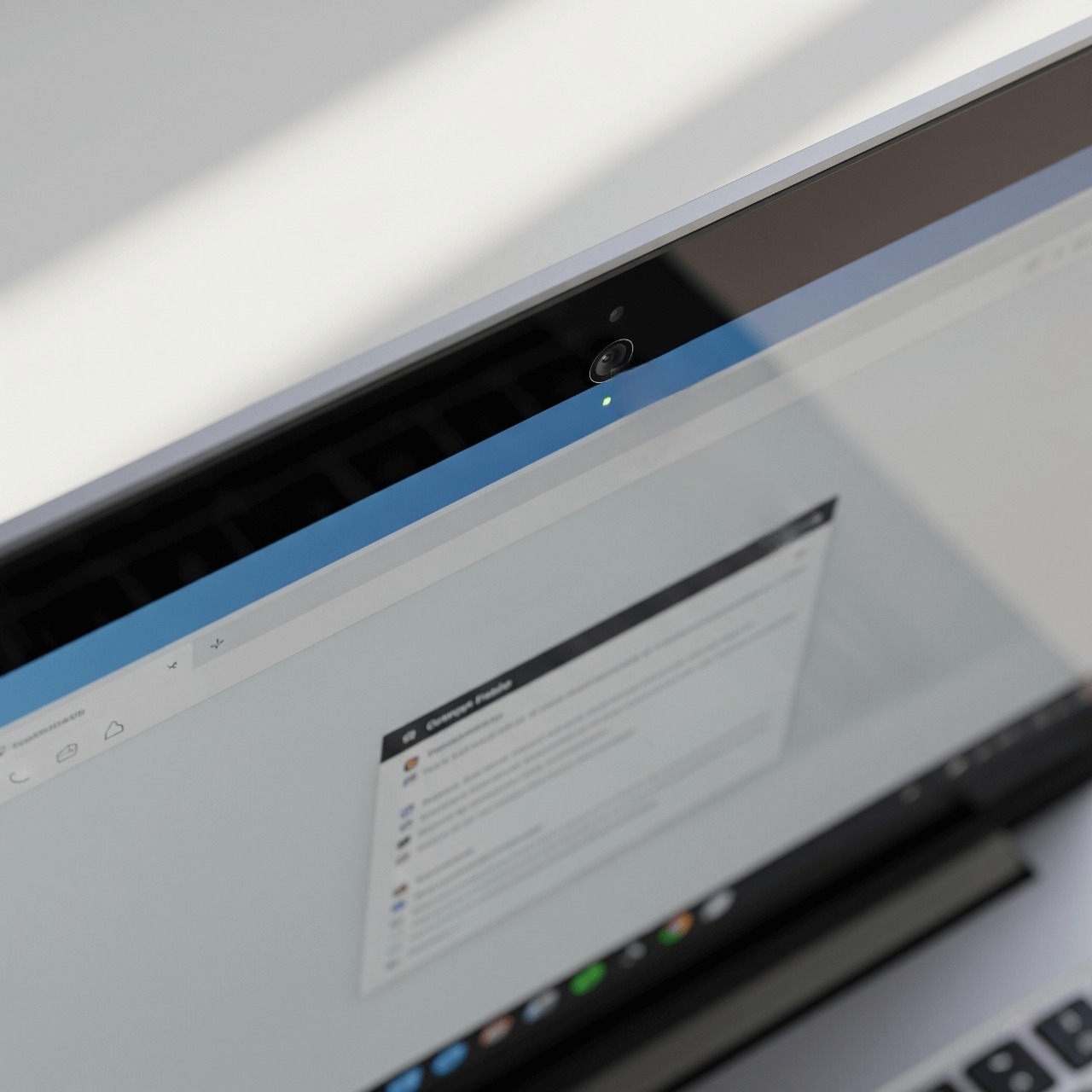 A laptop with an arrow pointing to the small microphone hole near the webcam.